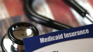 Tarjeta de Medicaid Insurance junto a un estetoscopio médico, ilustrando servicios de asistencia para seguros de salud.
