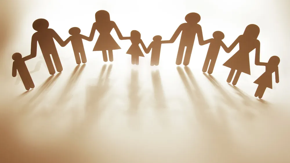 Cadena de figuras de papel de una familia unida, representando la unidad y el apoyo en servicios de inmigración o comunitarios.