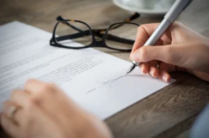 Persona firmando un documento oficial de registro de negocio con una pluma, ilustrando la apertura formal de una LLC o corporación.