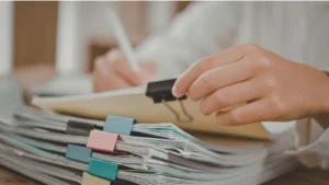 Persona organizando una pila de documentos oficiales con clips de colores, representando la preparación de trámites para servicio de apostilla.