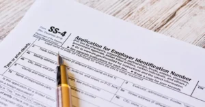 Primer plano del formulario SS-4 del IRS para la solicitud del Número de Identificación del Empleador (EIN) con un bolígrafo apoyado encima.